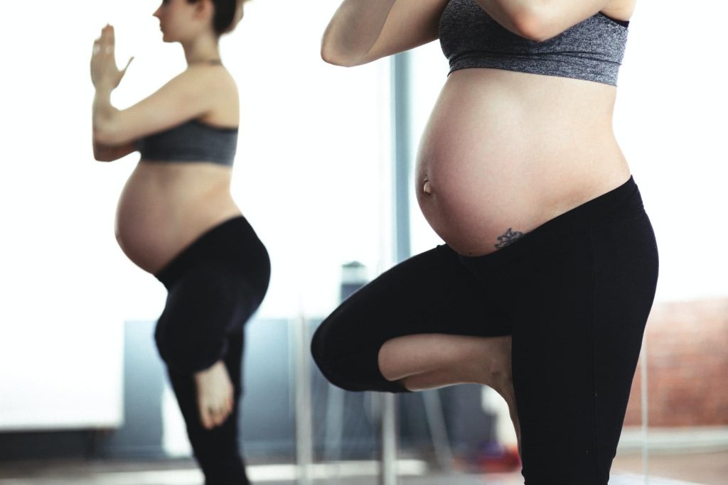 Mujer embarazada realizando yoga como hábito saludable.