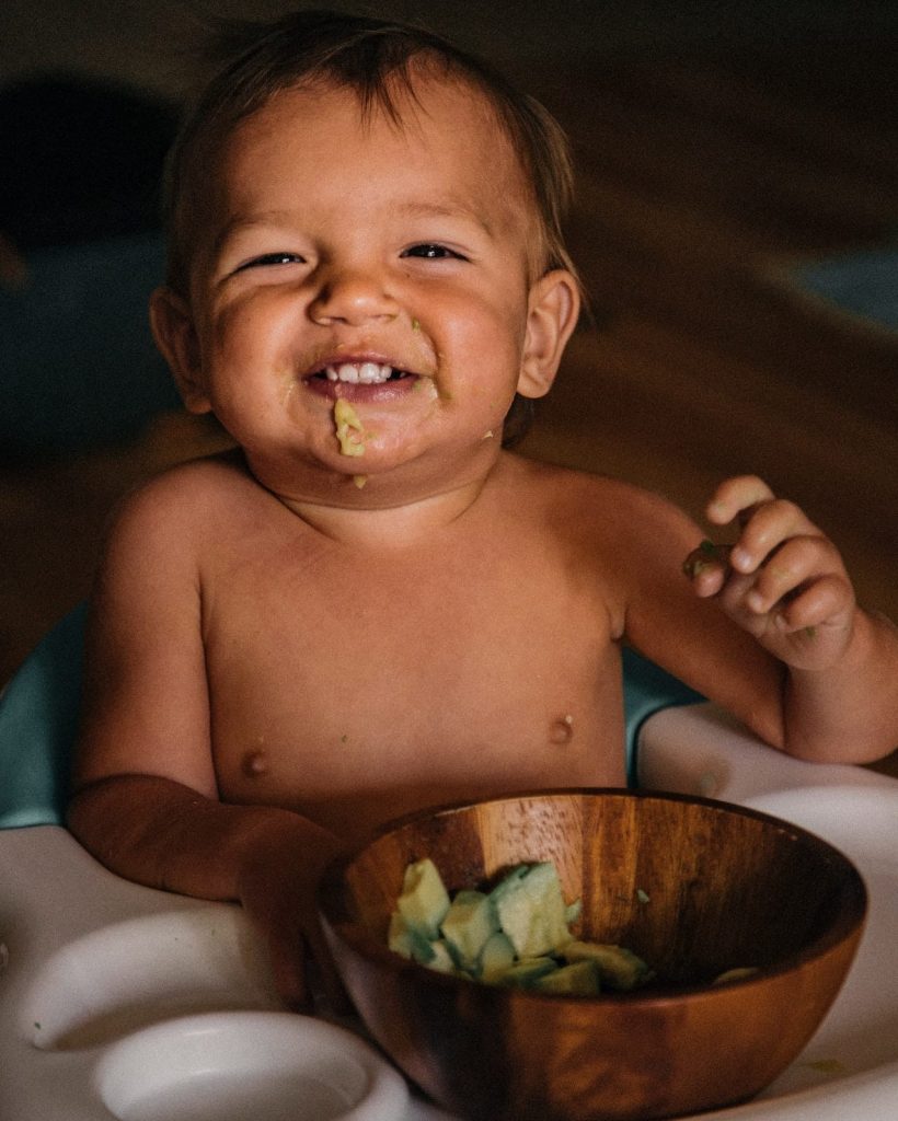 Bebé comiendo aguacate, una excelente fuente de grasa vegetal saludable.