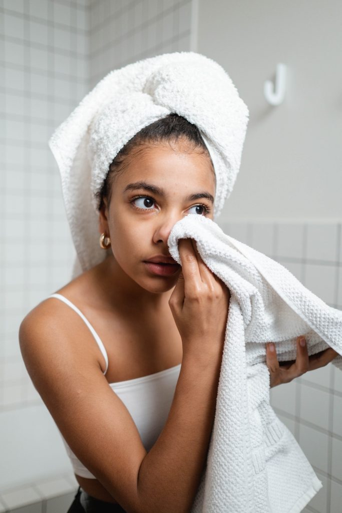 Mujer se esta secando su rostro para mantenerla seca y evitar infecciones por hongos en su piel.
